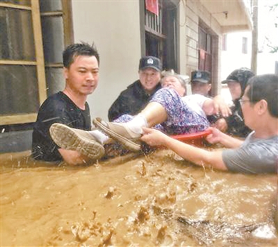 受台风“利奇马”影响，8月10日下午，安徽省宁国市宁墩镇老街受到洪水侵袭，当地村干部和干警正在将一位被困家中的老人转移到安全地带。李晓红 摄