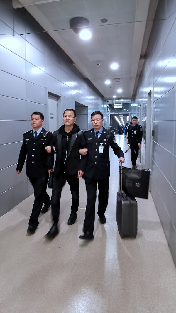 袁国方在机场边检人员的带领下离开飞机从登机口出来（胡高生 摄）