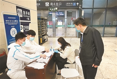 图为4月7日，张圣新（右一）正在武汉火车站检查返汉人员信息登记工作。王昆 摄
