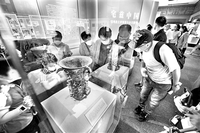 距今3000多年的青铜何尊，器内底部有122字铭文。其中的“宅兹中国”，是关于“中国”一词最早的文字记载，彰显了中华文化源远流长的独特魅力。图为2020年8月18日，观众在国家博物馆“宅兹中国——宝鸡出土青铜器与金文精华”展上观看展出的何尊。 （图片来源：视觉中国）