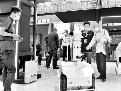 近日，工作人员（左一）在第三届中国粮食交易大会现场展示浪潮“巡仓机器人”。 蔡欣萍 摄