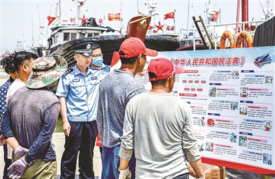 民法典表决通过后，各地结合实际开展多种形式的普法宣传。图为山东省东营市民警和社区网格员在渔港码头为渔民宣讲民法典内容。（图片来源：视觉中国）