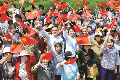 江西省德兴市香屯街道办江村千亩茶园，两名基层扶贫干部挥舞着党旗，和大家一起唱起了《唱支山歌给党听》。  （图片来源：视觉中国）